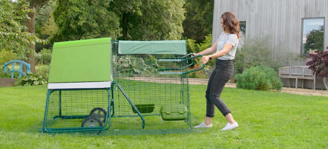 Eine frau bewegt einen Eglu Go hühnerstall