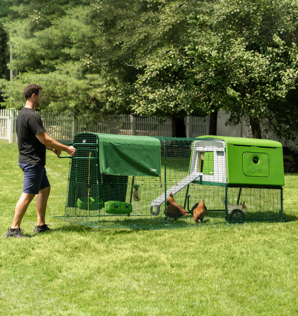 Mann bewegt den Eglu Cube tragbaren hühnerstall mit rädern und griffen