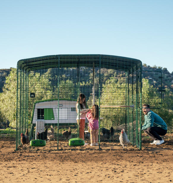 Familie mit ihrem Eglu pro hühnerstall und begehbarem auslauf, eingerichtet mit smart enabled Autodoor